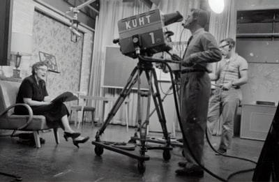 Man standing next to the studio camera, a woman holding a book sitting grayscale images
